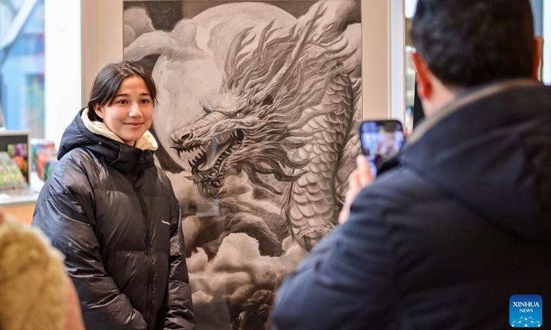 A visitor poses for a photo with an exhibit at a museum in Urumqi, capital of northwest China's Xinjiang Uygur Autonomous Region, Feb. 14, 2024. Many people choose to spend their Spring Festival holiday by viewing exhibitions in museums. (Photo: Xinhua)