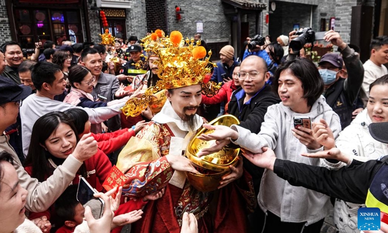 A staff member in the costume of the God of Wealth interacts with tourists in Nanning, south China's Guangxi Zhuang Autonomous Region, Feb. 14, 2024. Ceremonies were held Wednesday to welcome the God of Wealth as a tradition on the fifth day of the Chinese New Year. (Photo: Xinhua)