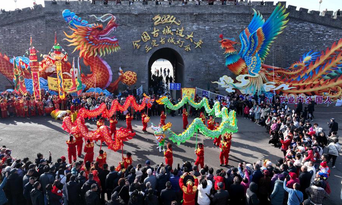 Tourists watch a dragon dance performance at the Zhengding ancient city in Shijiazhuang, north China's Hebei Province, Feb. 15, 2024. (Photo by Chen Qibao/Xinhua)