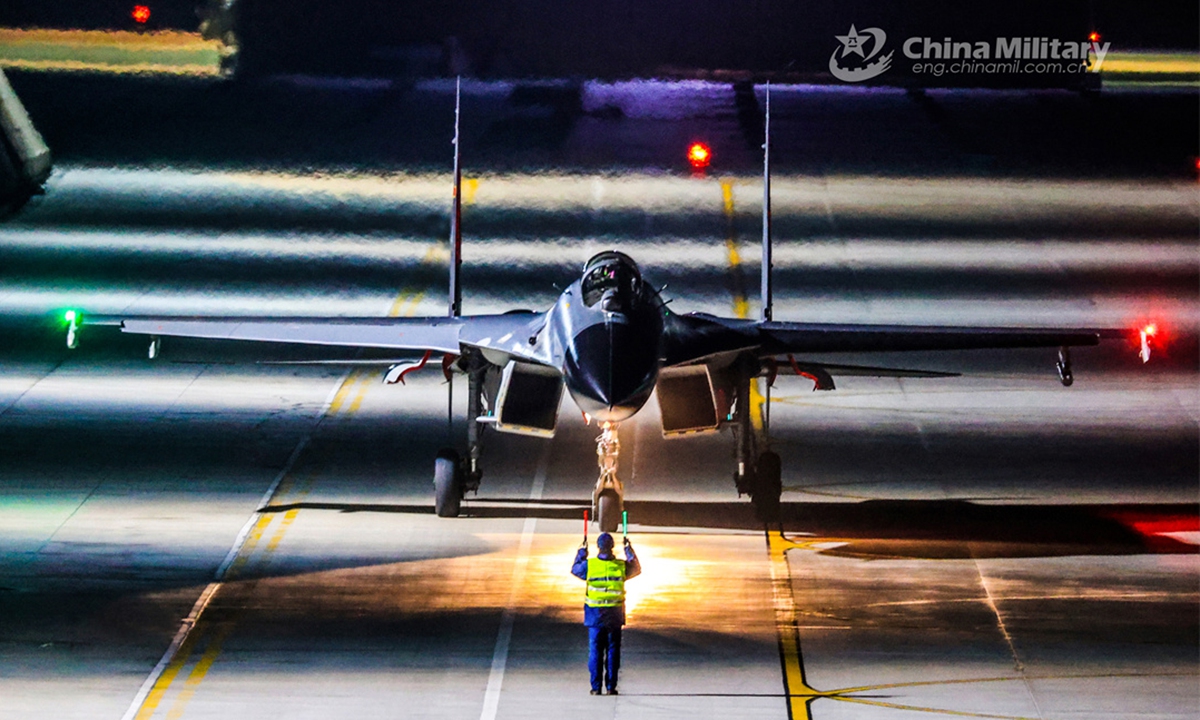 A ground crew member assigned to a brigade of the PLA Air Force Xi'an Flying College signals a pilot to taxi the fighter jet into the hangar during a 24-hour flight training exercise. (eng.chinamil.com.cn/Photo by Cui Baoliang)