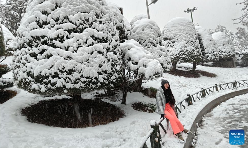 A woman takes photo amid snow at a park in Tehran, Iran, Feb. 25, 2024. (Xinhua/Shadati)