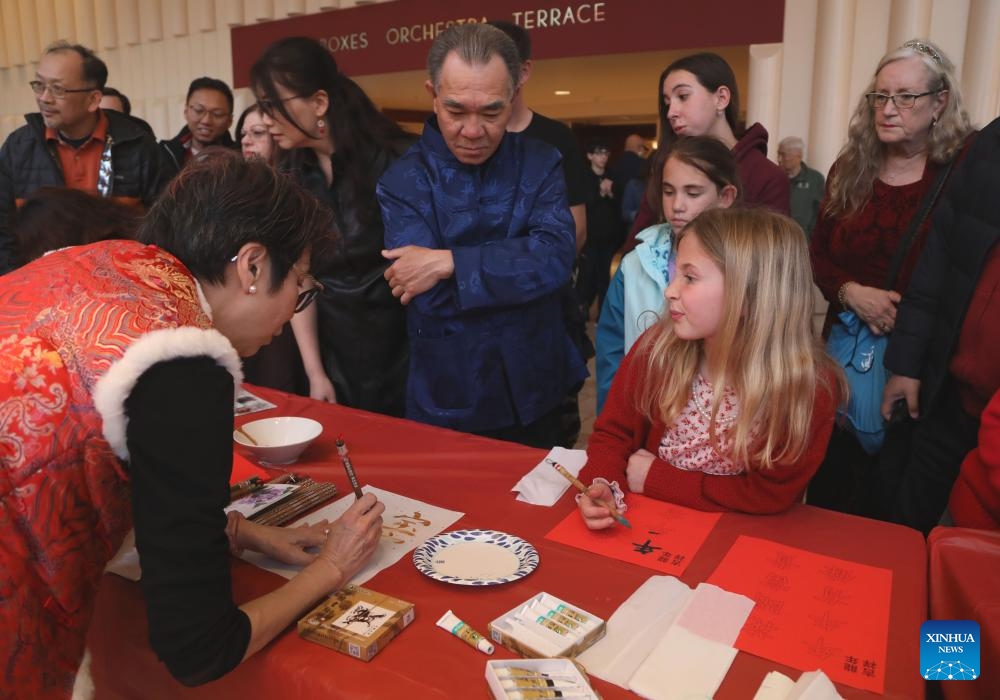 A girl learns Chinese calligraphy from a penman (L, front) at Davies Symphony Hall in San Francisco, California, the United States, Feb. 17, 2024. A concert in celebration of the Chinese Lunar New Year was staged here by San Francisco Symphony on Saturday.(Photo: Xinhua)