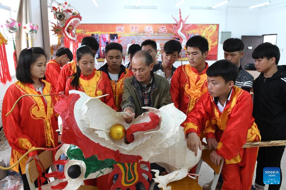 Craftsman Zou Yute (3rd L, front) shows techniques of making bamboo dragon for Firecracker Dragon Festival at a school in Binyang County in south China's Guangxi Zhuang Autonomous Region, Jan. 5, 2017. Firecracker Dragon Festival that can be dated back to more than 10 centuries ago is a traditional carnival celebrating Spring Festival in Binyang, when locals perform the firecracker dragon dance with a bamboo dragon.(Photo: Xinhua)