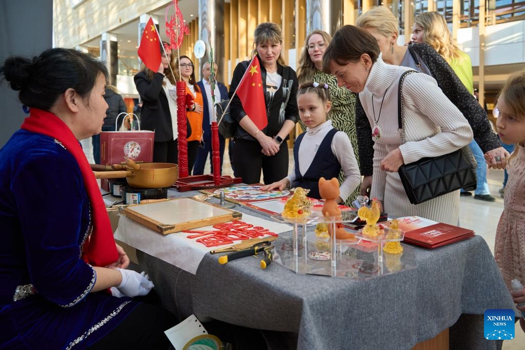 People visit a booth displaying sugar figures at an exhibition featuring intangible cultural heritages of China's Liaoning Province in Vladivostok, Russia, Feb. 20, 2024. An exhibition featuring intangible cultural heritages of China's Liaoning Province kicked off here on Tuesday. Chinese craftsmen demonstrated here their skills in making sugar figures, dough sculptures, finger paintings, amber carvings, and so on. The exhibition, attracting lots of visitors, will last till Feb. 25.(Photo: Xinhua)