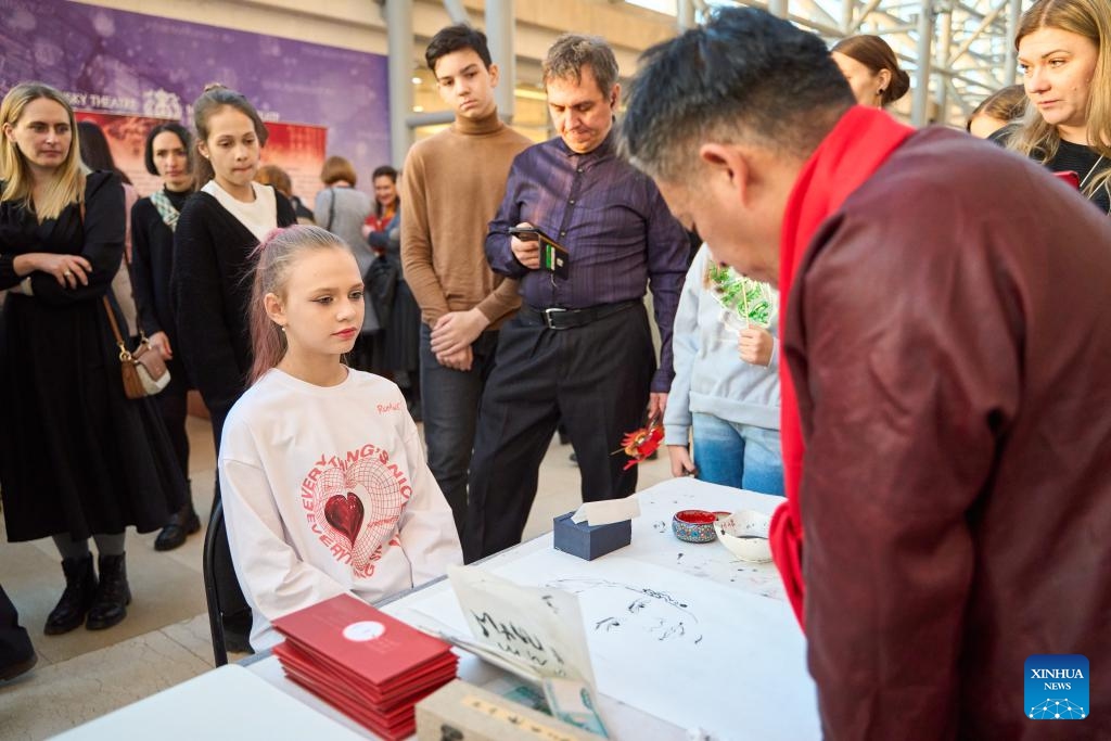 A Chinese craftsman makes a finger painting for a girl at an exhibition featuring intangible cultural heritages of China's Liaoning Province in Vladivostok, Russia, Feb. 20, 2024. An exhibition featuring intangible cultural heritages of China's Liaoning Province kicked off here on Tuesday. Chinese craftsmen demonstrated here their skills in making sugar figures, dough sculptures, finger paintings, amber carvings, and so on. The exhibition, attracting lots of visitors, will last till Feb. 25.(Photo: Xinhua)