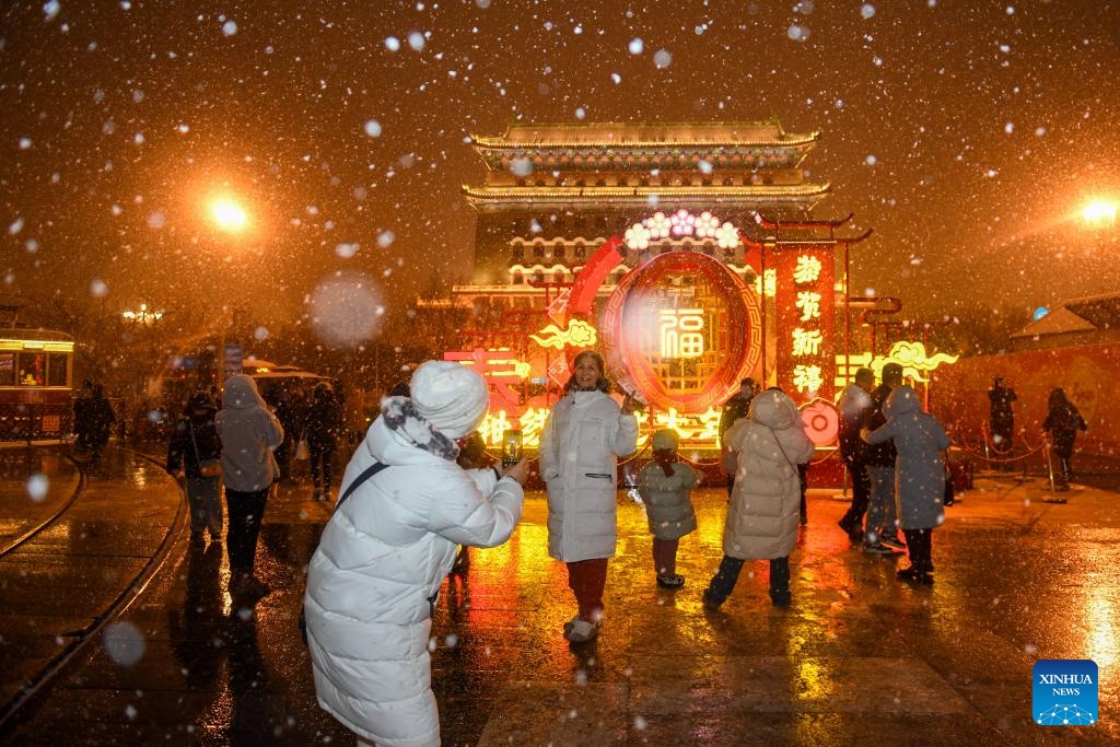 Tourists pose for photos in the snow at Qianmen Street in Beijing, capital of China, Feb. 20, 2024. Beijing saw a snowfall on Tuesday.(Photo: Xinhua)