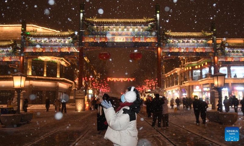 A woman enjoys the snow at Qianmen Street in Beijing, capital of China, Feb. 20, 2024. Beijing saw a snowfall on Tuesday.(Photo: Xinhua)