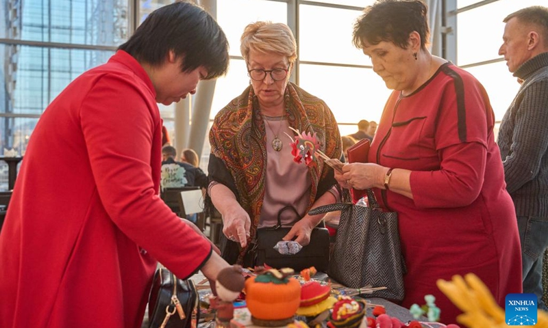 Visitors talk with a Chinese craftsman at an exhibition featuring intangible cultural heritages of China's Liaoning Province in Vladivostok, Russia, Feb. 20, 2024. An exhibition featuring intangible cultural heritages of China's Liaoning Province kicked off here on Tuesday. Chinese craftsmen demonstrated here their skills in making sugar figures, dough sculptures, finger paintings, amber carvings, and so on. The exhibition, attracting lots of visitors, will last till Feb. 25.(Photo: Xinhua)