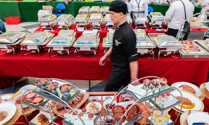 A chef walks past pork dishes in a Guinness World Record attempt during the National Hog Festival in Quezon City, the Philippines, on March 1, 2024. Hog farmers in Quezon City set the Guinness World Record for the most varieties of pork dishes on display during the launch of the five-day National Hog Festival on Friday. (Photo: Xinhua)