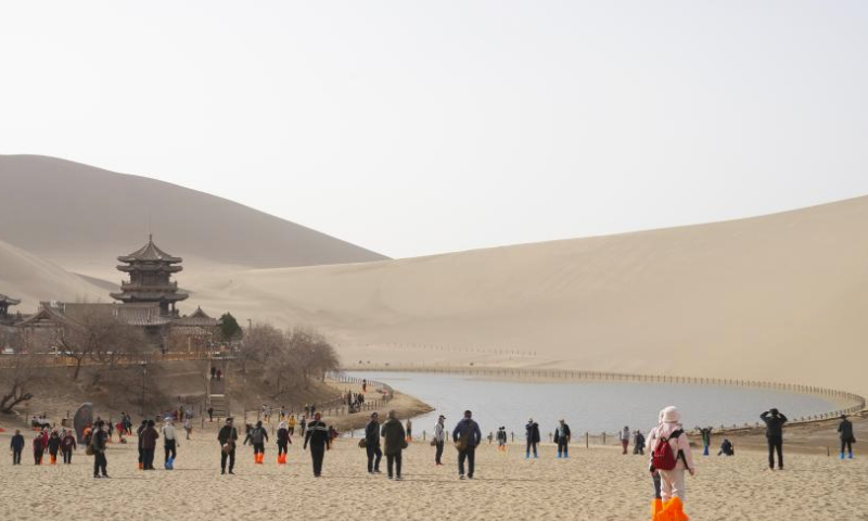 Tourists visit the Mingsha Mountain and Crescent Spring scenic spot in Dunhuang, northwest China's Gansu Province, March 16, 2024. Dunhuang has received a total of 336,000 tourists from Jan. 1 to March 16 this year, an increase of 86.6 percent over the same period in 2023. (Xinhua/Zhang Zhimin)