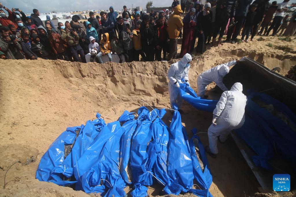 Palestinian workers bury bodies at a grave for victims killed in the Hamas-Israel conflict in the southern Gaza Strip city of Rafah, on March 7, 2024. The Palestinian death toll in the Gaza Strip has risen to 30,800 since the outbreak of the Israel-Hamas conflict on Oct. 7, 2023, the Hamas-run Health Ministry said in a press statement on Thursday.(Photo: Xinhua)