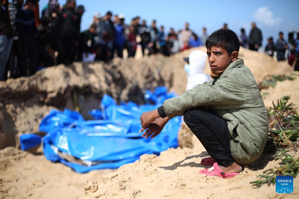 A Palestinian boy squats by a grave for victims killed in the Hamas-Israel conflict in the southern Gaza Strip city of Rafah, on March 7, 2024. The Palestinian death toll in the Gaza Strip has risen to 30,800 since the outbreak of the Israel-Hamas conflict on Oct. 7, 2023, the Hamas-run Health Ministry said in a press statement on Thursday. (Photo: Xinhua)