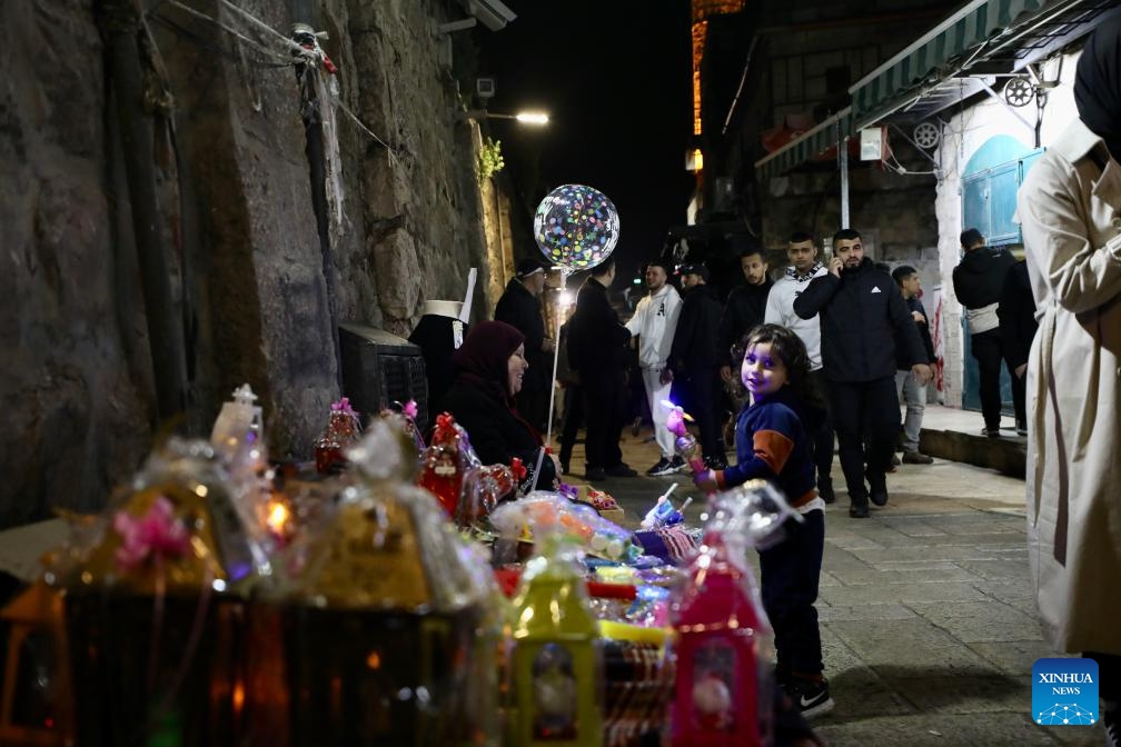 A girl stands by a stall of decorations during Ramadan in Jerusalem's Old City, on March 12, 2024.(Photo: Xinhua)