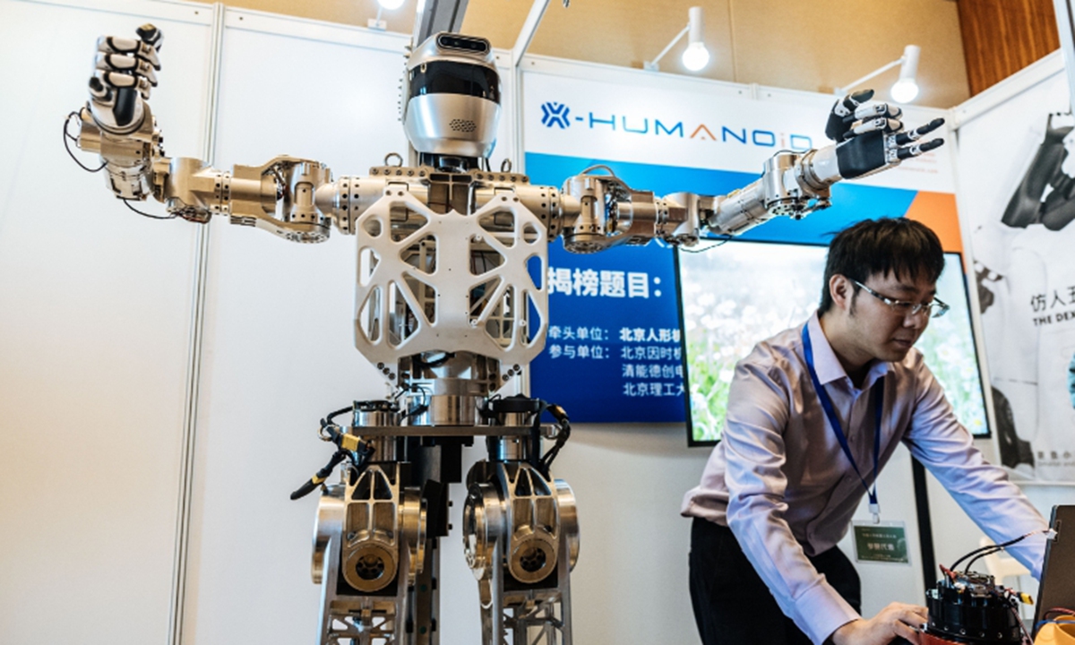 A participant and a robot are seen at a humanoid robot competition hosted by the Chinese Institute of Electronics which kicked off in Yizhuang, Beijing, on March 13. More than 120 projects are participating in the competition, covering domestic leading companies, universities and research institutes in various fields, including complete humanoid robots and core components. This is a top competition among leaders in various fields of humanoid robots in China.  Photo: Li Hao/GT 