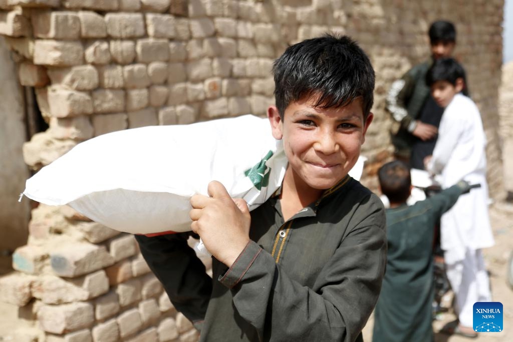 A boy smiles as he receives a bag of gifts from Chinese and Pakistani volunteers at a slum in Islamabad, Pakistan, on March 17, 2024. A group of a dozen Chinese and Pakistani volunteers associated with China-Pakistan Youth Exchange Community, and Beijing One Heart Sphere Charity Foundation visited two schools and delivered about 200 donation bags of gifts to children and women.(Photo: Xinhua)