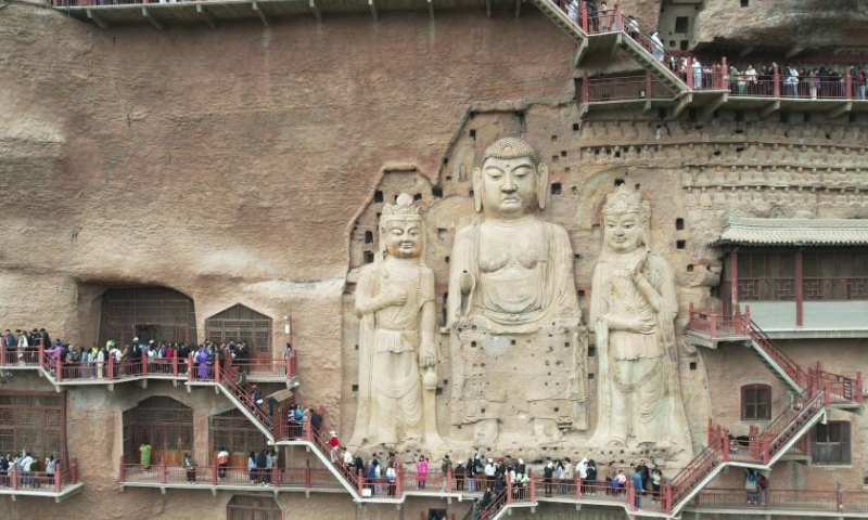 A drone photo taken on April 5, 2024 shows tourists visiting the Maiji Mountain Grottoes in Maiji District of Tianshui City, northwest China's Gansu Province. Tianshui has garnered considerable attention in the cyber world thanks to the popularity of Tianshui's malatang, a numbing-spicy hotpot. When it comes to the real world, the city received 309,000 and 348,600 tourists on April 4 and 5, the first two day of the three-day Qingming holiday, with tourism-related revenue of 177 million yuan (about 24.47 million U.S. dollars) and 198 million yuan (about 27.37 million U.S. dollars), respectively. (Xinhua/Zhang Zhimin)