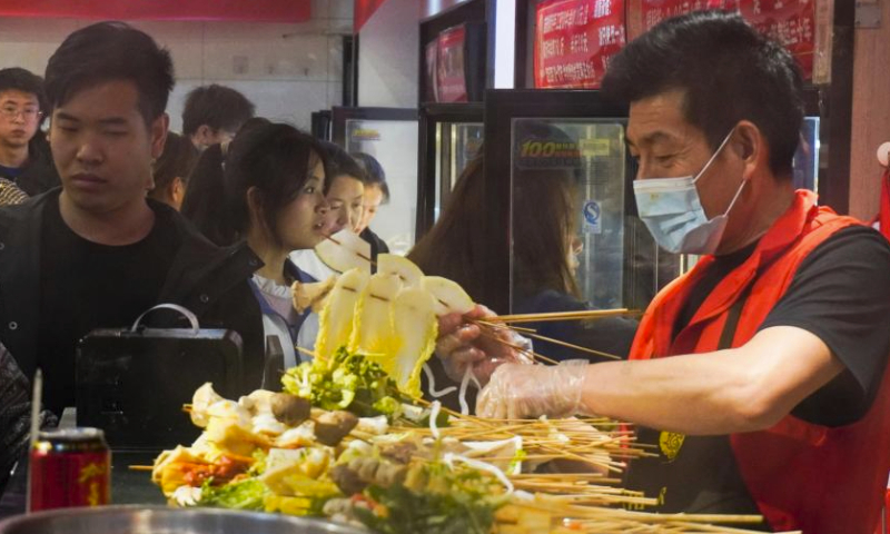 A staff member cooks malatang at a store in Maiji District of Tianshui City, northwest China's Gansu Province, April 3, 2024. Tianshui has garnered considerable attention in the cyber world thanks to the popularity of Tianshui's malatang, a numbing-spicy hotpot. When it comes to the real world, the city received 309,000 and 348,600 tourists on April 4 and 5, the first two day of the three-day Qingming holiday, with tourism-related revenue of 177 million yuan (about 24.47 million U.S. dollars) and 198 million yuan (about 27.37 million U.S. dollars), respectively. (Xinhua/Ma Xiping)