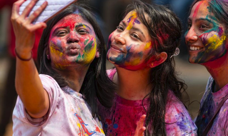 Girls smeared with colored powder take selfies during the celebration of the Holi Festival at Patan Durbar Square in Lalitpur, Nepal, March 24, 2024. Holi, the festival of colors, marks the beginning of the spring season. (Photo by Hari Maharjan/Xinhua)