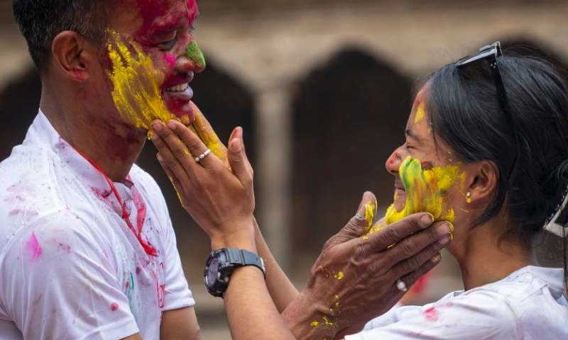 People smear colored powder on each other's faces during the celebration of the Holi Festival at Patan Durbar Square in Lalitpur, Nepal, March 24, 2024. Holi, the festival of colors, marks the beginning of the spring season. (Photo by Hari Maharjan/Xinhua)
