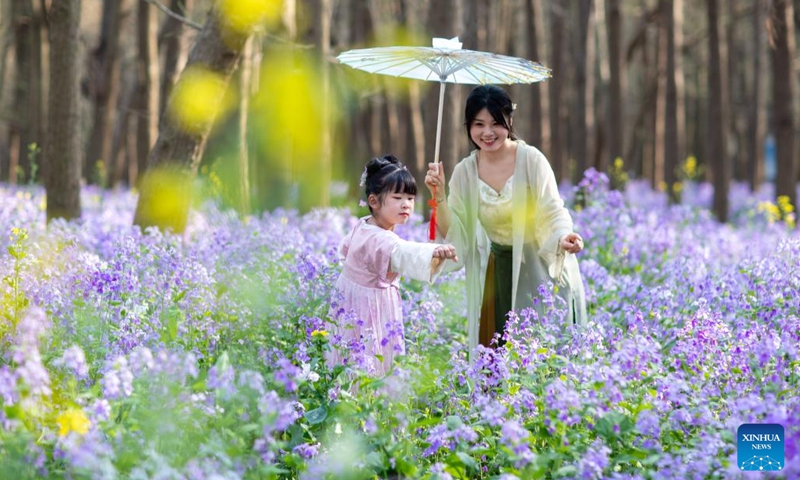 Tourists wearing traditional costumes view flowers at a wetland park in Xinghua City, east China's Jiangsu Province, March 31, 2024. (Photo by Zhou Shegen/Xinhua)