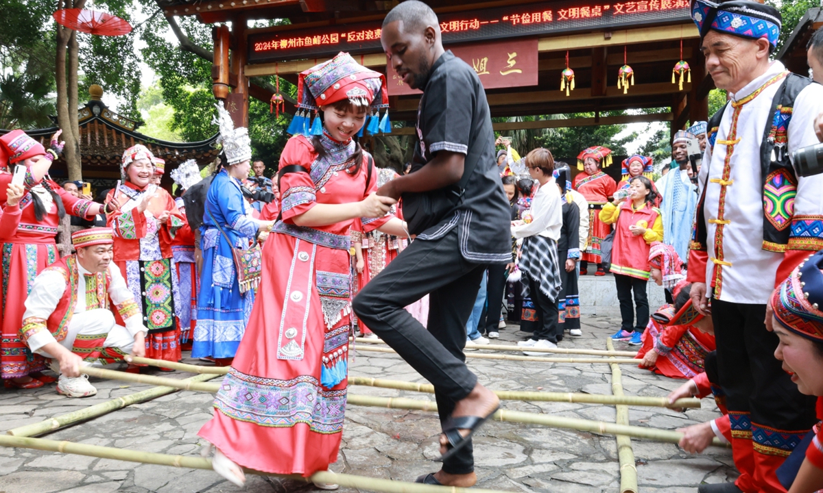 An international student participates in a bamboo pole dance with a local girl in Liuzhou, South China's Guangxi Zhuang Autonomous Region, on April 8, 2024. Nearly 30 international students were invited to experience traditional customs before the arrival of the Sanyuesan Festival, which falls on the third day of the third lunar month. Photo: VCG