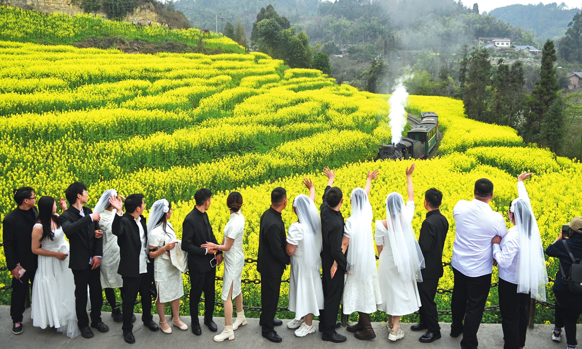 The newlyweds participating in the collective wedding watch the sea of flowers and the small train at Duanjiawan station, in Qianwei, Southwest China's Sichuan Province on March 12, 2024. Photo: IC