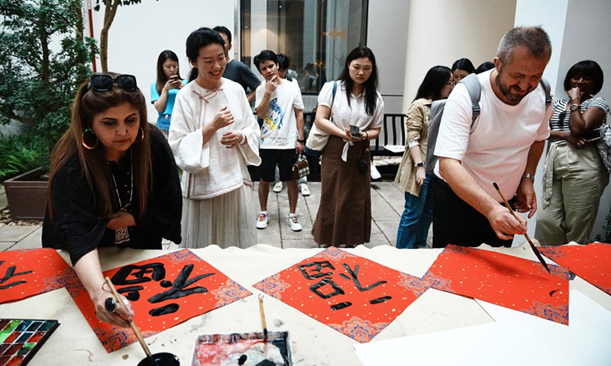 Two recipients of the first Silk Road Global News Awards (SRGNA) draw ink-and-wash paintings of Bombax ceiba, the city flower of Guangzhou, during a cultural exchange event held in Yongqing Fang historical alleyways of Guangzhou, south China's Guangdong Province. (Photo/Yang Shuobi and Wang Yan)