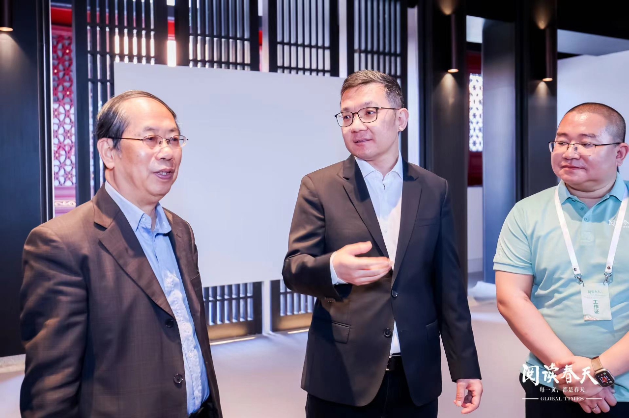 Fan Zhengwei (center) introduces the exhibition of the 15th anniversary of the Global Times English Edition to the guests.