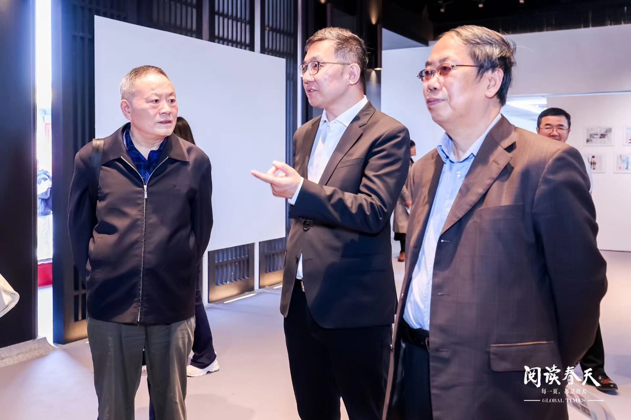 Fan Zhengwei (center) introduces the exhibition of the 15th anniversary of the Global Times English Edition to the guests.