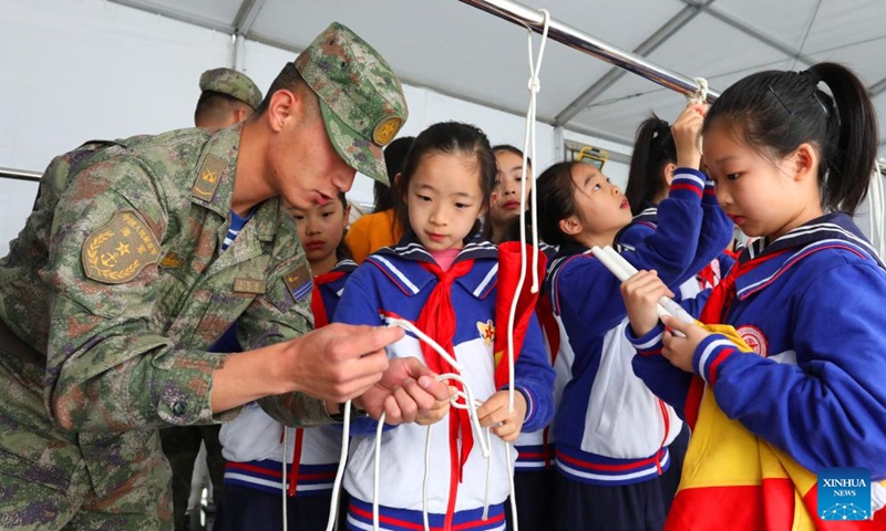 Children learn to tie knot under the guidance of naval soldiers during an open day event at a port in east China's Shanghai, April 23, 2024. The Chinese People's Liberation Army Navy holds open day events in Shanghai on Tuesday to mark the 75th anniversary of its founding. Visitors could tour the guided-missile destroyer Zibo and hospital ship Peace Ark at the event.(Photo: Xinhua)