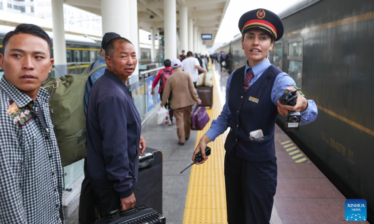 Airkir Duliki (R) helps passengers board a train from Chengdu to Kashgar at a railway station in Chengdu, southwest China's Sichuan Province, April 20, 2024. Airkir Duliki, the 27-year-old ethnic Tajik train conductor, was born and raised amidst the snow-capped mountains and grasslands in a village of Taxkorgan Tajik Autonomous County on the Pamir Plateau, where railways were not common for residents in the past. (Photo: Xinhua)