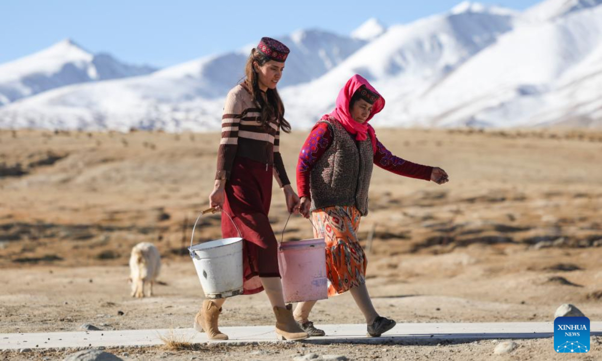 Airkir Duliki (L) helps her mother carry water at Taxkorgan Tajik Autonomous County in northwest China's Xinjiang Uygur Autonomous Region, March 23, 2024. Airkir Duliki, the 27-year-old ethnic Tajik train conductor, was born and raised amidst the snow-capped mountains and grasslands in a village of Taxkorgan Tajik Autonomous County on the Pamir Plateau, where railways were not common for residents in the past. (Photo: Xinhua)