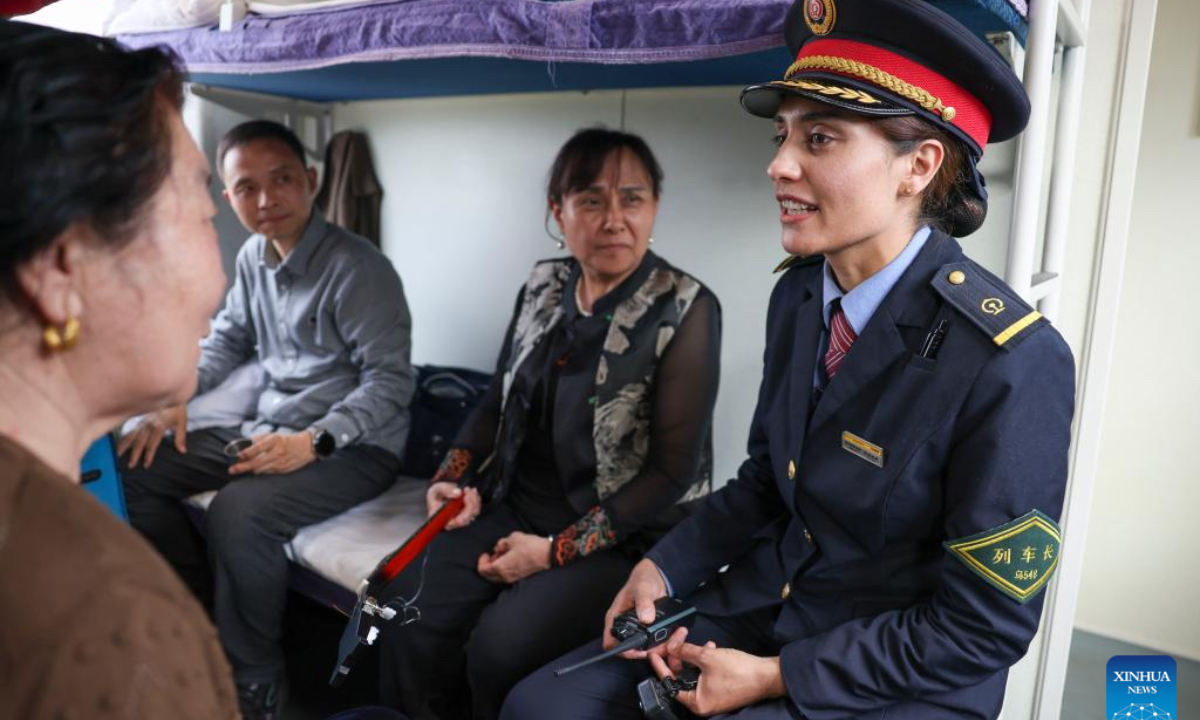 Airkir Duliki (1st R) talks with passengers on a train from Kashgar to Chengdu in China, April 19, 2024. Airkir Duliki, the 27-year-old ethnic Tajik train conductor, was born and raised amidst the snow-capped mountains and grasslands in a village of Taxkorgan Tajik Autonomous County on the Pamir Plateau, where railways were not common for residents in the past. (Photo: Xinhua)