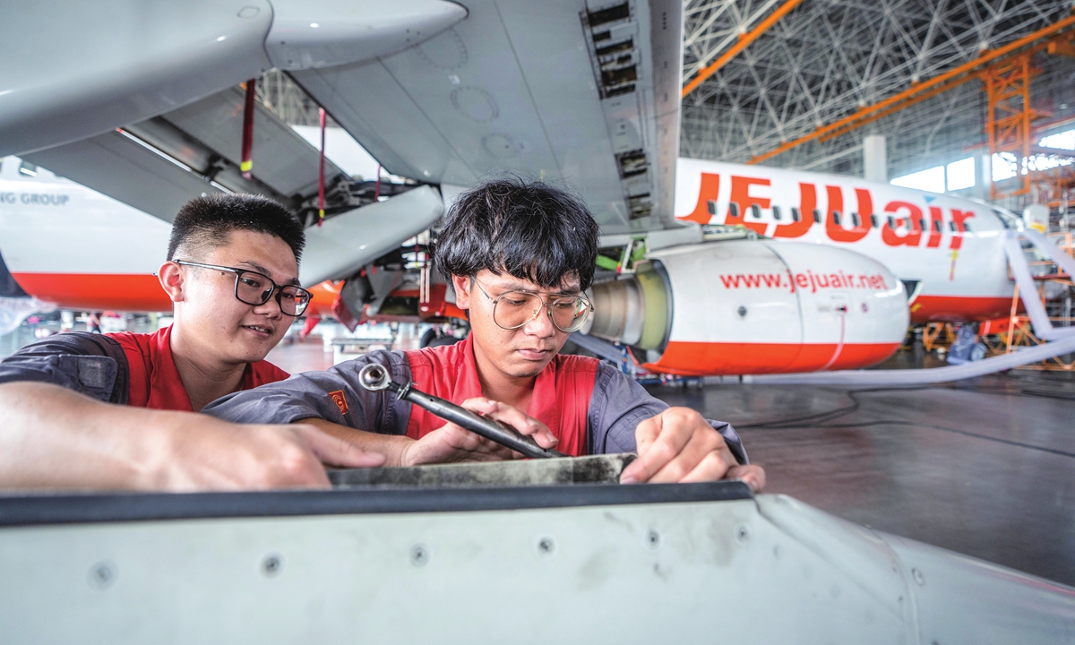 Two workers from an aircraft maintenance service company overhaul an aircraft of a South Korean airline in Haikou, South China's Hainan Province on May 10, 2024. It is the first time the Hainan Free Trade Port has conducted maintenance business for South Korea's inbound aircraft, and also the first inbound aircraft maintenance order from Northeast Asia, further broadening the port's aircraft maintenance market. Photo: VCG