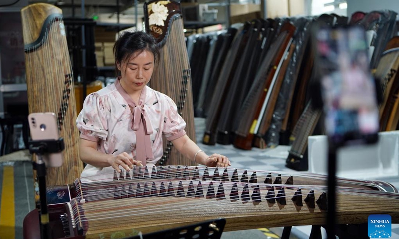 A staff member sells guzheng, also known as Chinese zither, via livestreaming in Lankao County of Kaifeng City, central China's Henan Province, May 13, 2024. In recent years, Lankao County has vigorously developed the traditional musical instrument industry in an effort to fully utilize paulownia trees, which are bountiful in the county.(Photo: Xinhua)