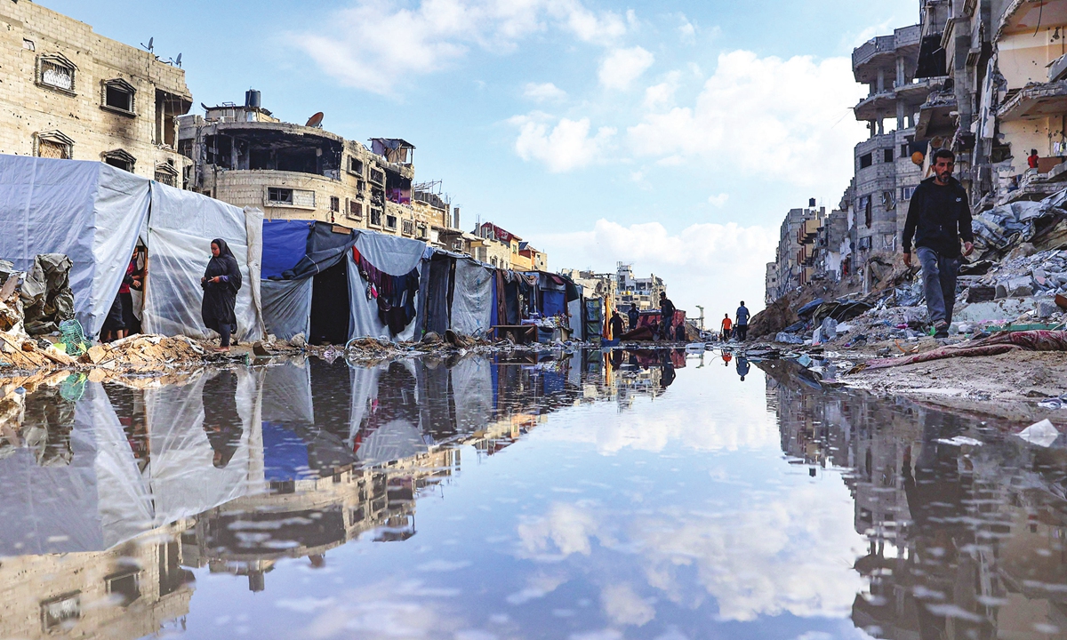 Displaced Palestinians walk around a large pool of water in front of destroyed buildings and tents in Khan Yunis in the southern Gaza Strip on May 16, 2024, amid the ongoing conflict. Israelis have now killed at least 502 Palestinians in the occupied West Bank since October 7, 2023, media reported. 
Photo: VCG