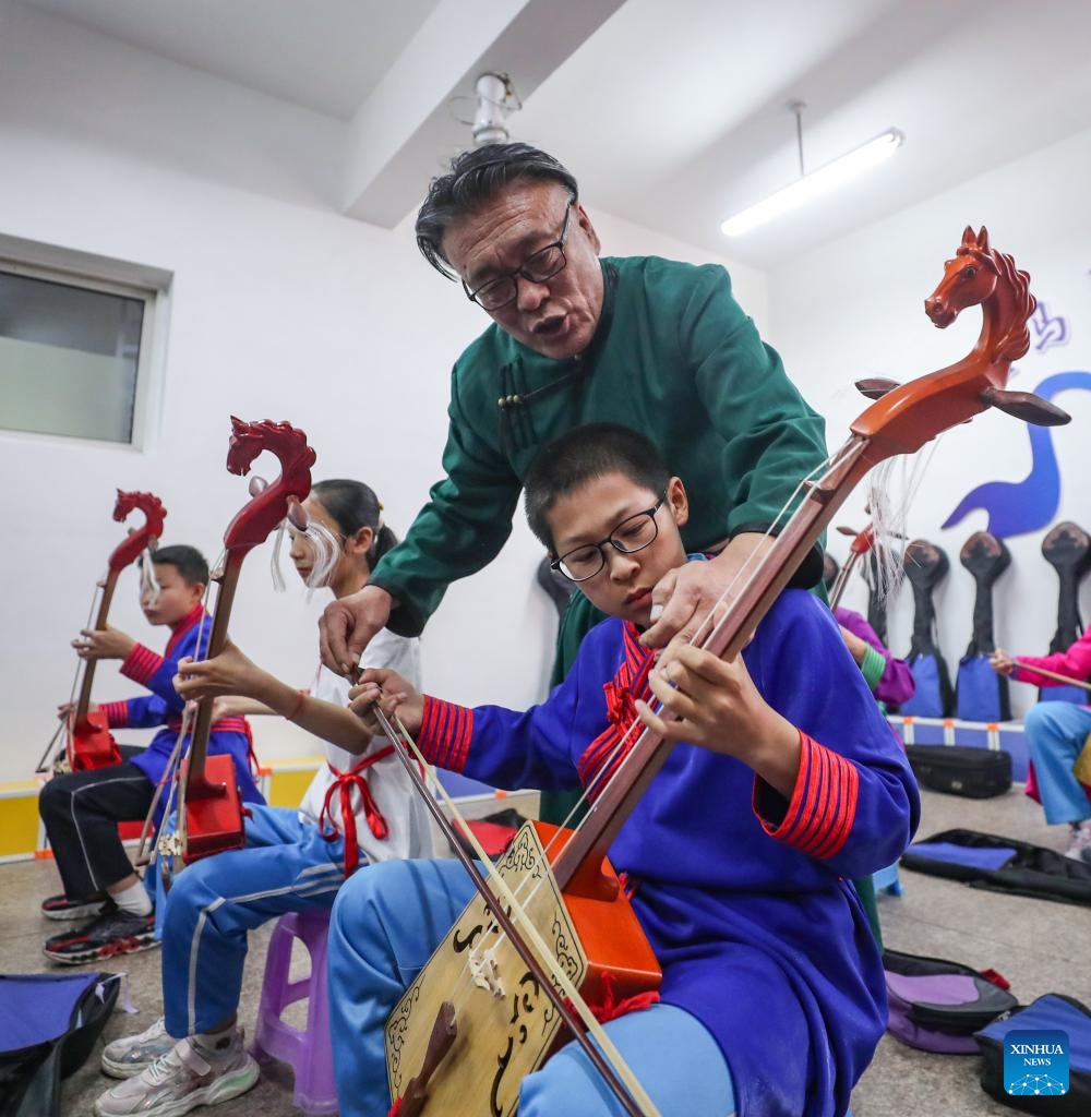 Teacher Wu Fulin teaches a student to practice horse-head fiddle at a primary school in Fuxin Mongolian Autonomous County, northeast China's Liaoning Province, May 15, 2024. Fuxin has stepped up efforts in protection and inheritance of traditional Mongolian ethnic culture by offering students various lessons such as horse-head fiddle and Mongolian dance, etc. to help bring new vitality to traditional ethnic culture.(Photo: Xinhua)