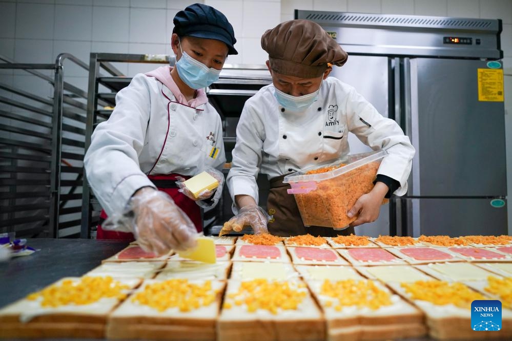 Fu Fu (R) and his colleague Xiaomeng make sandwiches at Amity Bakery in Nanjing, east China's Jiangsu Province, May 15, 2024.(Photo: Xinhua)