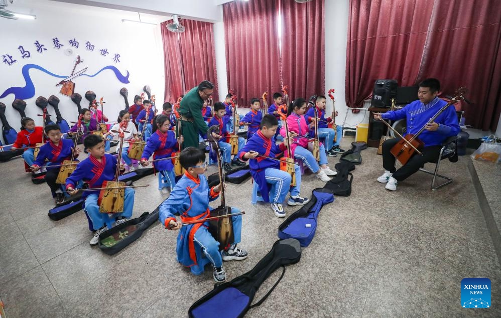 Teacher Wu Fulin and an inheritor of horse-head fiddle instruct students to practice horse-head fiddle at a primary school in Fuxin Mongolian Autonomous County, northeast China's Liaoning Province, May 15, 2024. Fuxin has stepped up efforts in protection and inheritance of traditional Mongolian ethnic culture by offering students various lessons such as horse-head fiddle and Mongolian dance, etc. to help bring new vitality to traditional ethnic culture.(Photo: Xinhua)