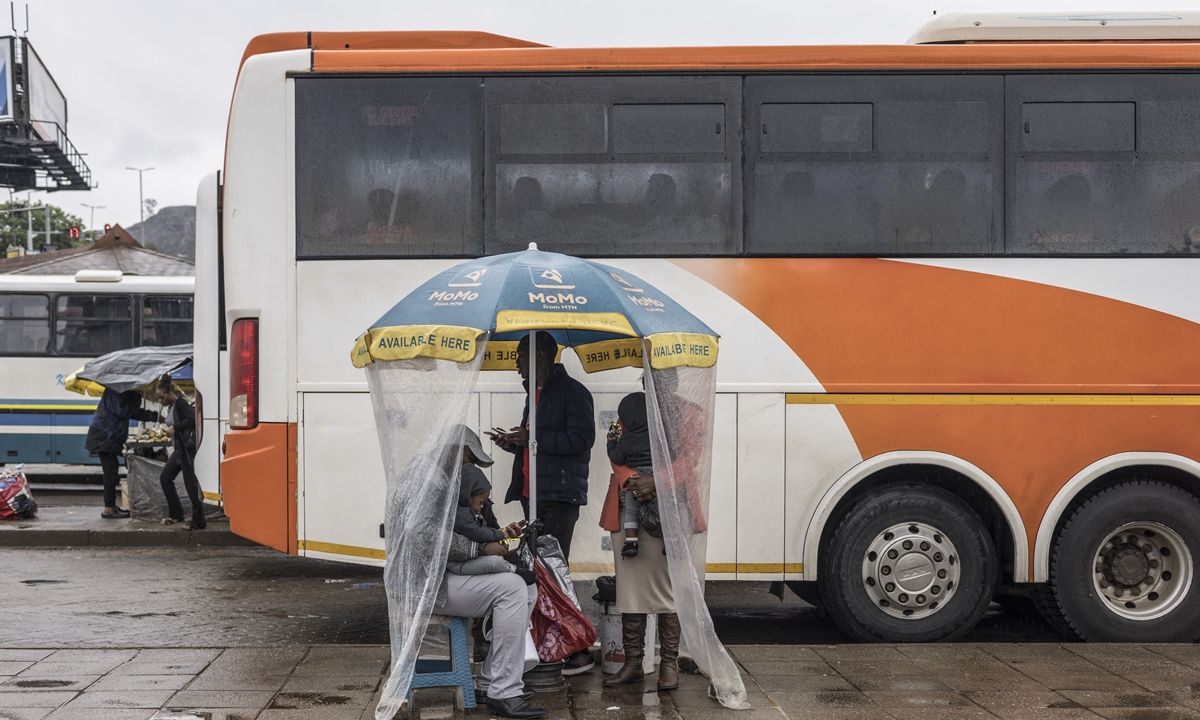 Pedestrians take shelter from the rain on the streets of Mbabane, the capital city of Eswatini, on September 28, 2023. Photo: AFP
