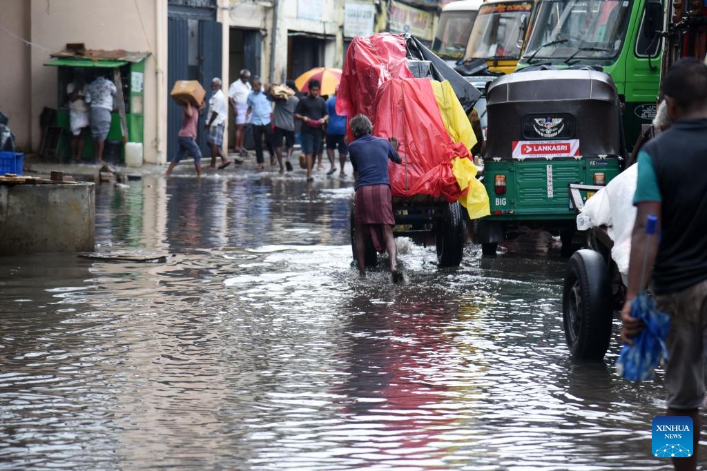 People wade through a waterlogged road in Colombo, Sri Lanka, May 21, 2024. Over 33,000 people in Sri Lanka remain affected by the adverse weather conditions, an official said on Tuesday.(Photo: Xinhua)