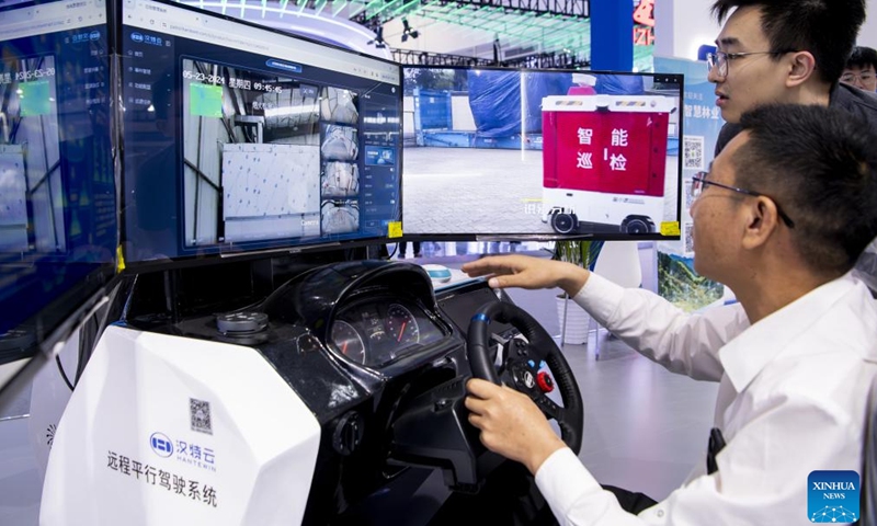 A visitor (R) tries remote parallel driving system at the on-site experience area for the 7th Digital China Summit in Fuzhou, southeast China's Fujian Province, May 23, 2024. The 7th Digital China Summit will take place in Fuzhou from May 24 to 25. The preview of its on-site experience area, covering an area of 56,000 square meters and consisting of five major parts, was opened at Fuzhou Strait International Conference and Exhibition Center on Thursday.(Photo: Xinhua)