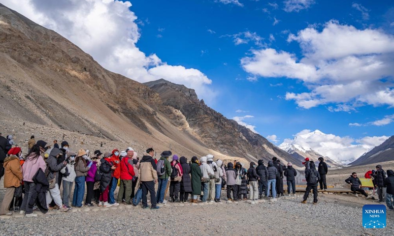 Tourists line up to take photos at the foot of Mount Qomolangma in southwest China's Xizang Autonomous Region, May 24, 2024. The Mount Qomolangma National Park has entered peak tourism season. From Jan. 1 to May 20 this year, the Mount Qomolangma scenic spot has received about 136,000 tourists. (Photo:Xinhua)