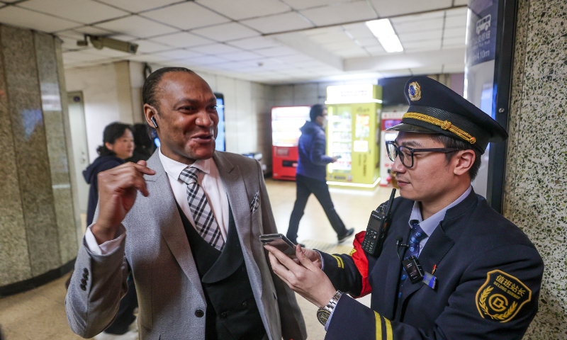 A staff member of Dongzhimen subway station answers questions from a foreign passenger through a translator machine in Beijing, on March 29, 2024. Photo: VCG