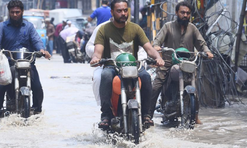 People riding motorbikes wade through a flooded road after heavy rain in southern Pakistani port city of Karachi on July 20, 2024. (Str/Xinhua)