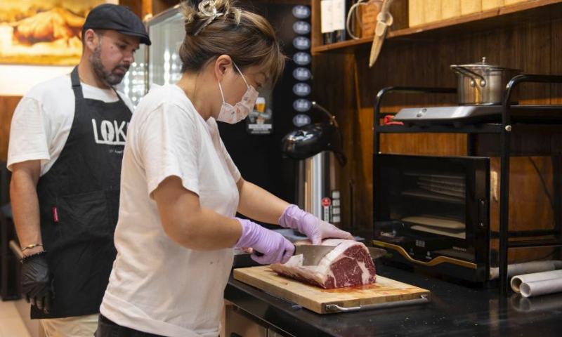 Gabriel Martin's wife Zhang Jin (R) cuts steaks at LOKO steakhouse in the ancient city of Wuhu in Wuhu City, east China's Anhui Province, June 20, 2024.(Xinhua/Fu Tian)