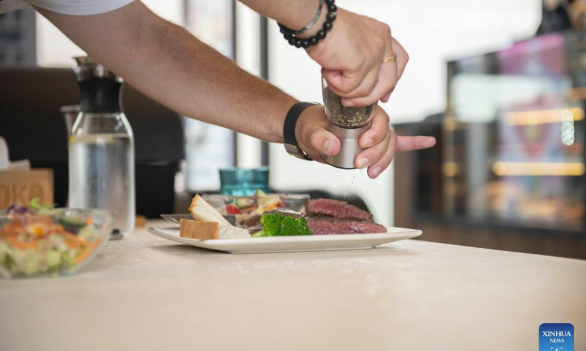 Gabriel Martin seasons the steak at LOKO steakhouse in the ancient city of Wuhu in Wuhu City, east China's Anhui Province, June 20, 2024.(Xinhua/Fu Tian)