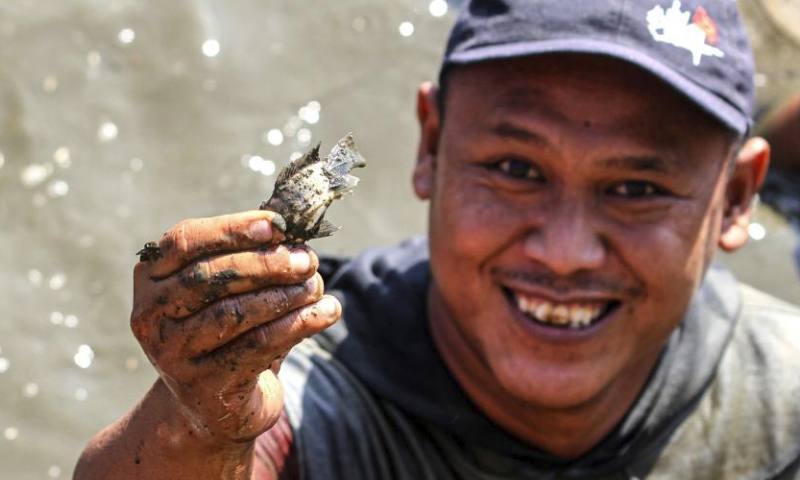 A man presents a small fish he caught during Festival Memet Ikan, or fish catching festival, at Gemblegan village in Klaten regency, Central Java, Indonesia, July 21, 2024. (Photo by Bram Selo/Xinhua)