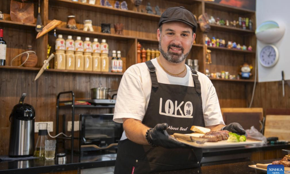 Gabriel Martin displays the steak he just cooked at LOKO steakhouse in the ancient city of Wuhu in Wuhu City, east China's Anhui Province, June 20, 2024.(Xinhua/Fu Tian)