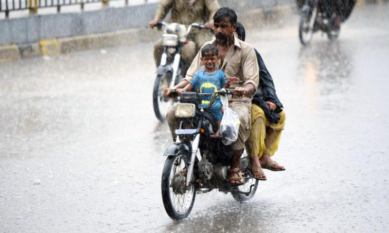 People ride motorbikes on a road during heavy rain in southern Pakistani port city of Karachi on July 20, 2024. (Str/Xinhua)